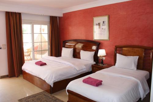 沙姆沙伊赫Herrmes Hospitality的红色墙壁客房的两张床