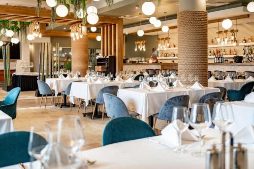 茹里洛夫卡Razelm Luxury Resort的用餐室配有白色的桌子和蓝色的椅子