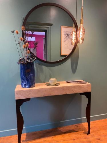 欧坦Suite avec Spa Quartier Cathédrale的一张桌子上挂着镜子和蓝色花瓶
