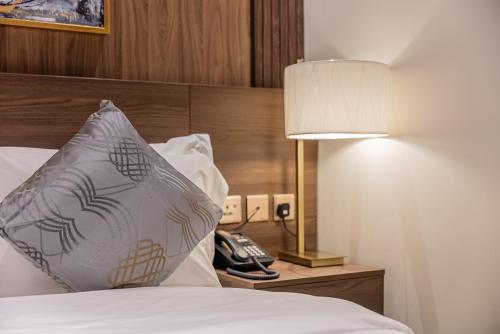 巴勒如拉斯DiYar Home Hotel的一间设有一张带台灯和电话的床的房间