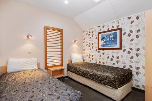 陶波Midtown Tui Villa - Taupō Central Holiday Unit的一间卧室设有两张床和窗户。