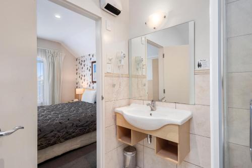 陶波Midtown Tui Villa - Taupō Central Holiday Unit的一间带水槽和镜子的浴室以及一张床