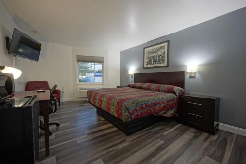 博林Greenwoods inn & Suites的一间卧室配有一张床、一张书桌和一台电视
