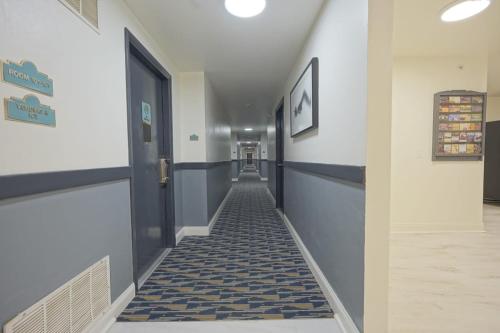 博林Greenwoods inn & Suites的走廊拥有蓝色和白色的墙壁,铺有瓷砖地板。