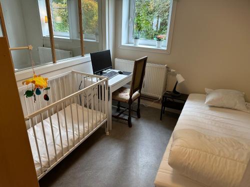 博伦厄Lärkan21 Tvisegatan 24C的一间卧室配有婴儿床和一张带笔记本电脑的书桌。