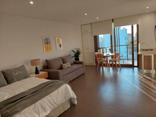 马德普拉塔EXCELENTE y completisimo monoambiente con cochera的一间卧室配有一张床、一张沙发和一张桌子