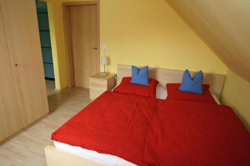 PouchFerienhaus Halbritter Pouch的一间卧室配有红色的床和蓝色枕头
