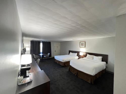 CochraneTravelodge by Wyndham Cochrane的酒店客房配有两张床和一张书桌
