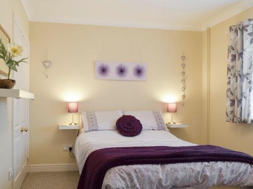 Birtsmorton莉娜山林小屋酒店的一间卧室配有一张带紫色毯子的床