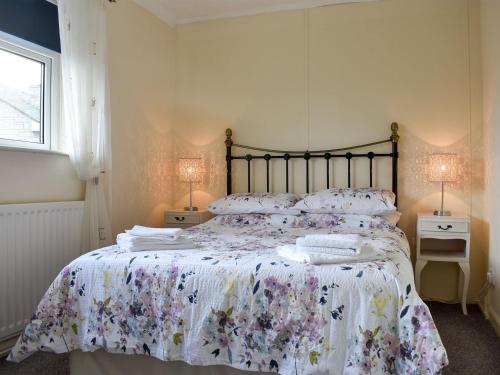 HamsterleyCotswolds Cottage的一间卧室配有一张带花卉床罩和两盏灯的床。