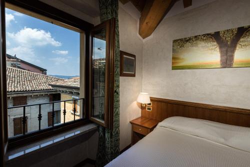 西尔米奥奈科特蕾佳娜酒店的一间卧室设有一张床和一个大窗户