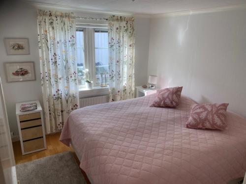 谢尔港Bekvämt boende mitt i gamla genuina Skärhamn的一间卧室配有一张带粉色床单的床和一扇窗户。