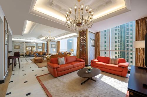多哈Dusit Hotel & Suites - Doha的客厅配有红色家具和吊灯。