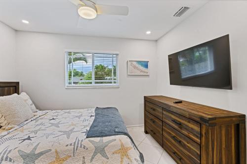 北棕榈滩Cinderella's Beach Cottage的一间卧室配有一张床和一台平面电视