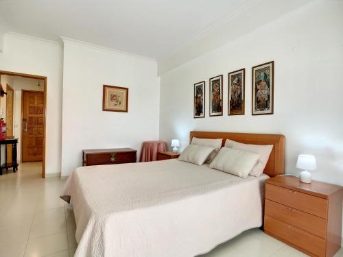 珀彻斯O Cantinho do Algarve的白色卧室配有一张床,墙上挂有两张照片