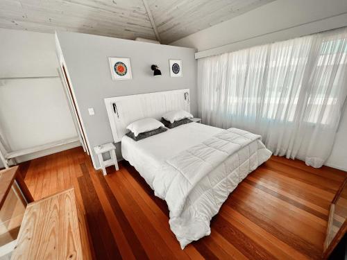埃斯特角城Punta Ballena Punta del Este的卧室配有一张白色的大床,铺有木地板
