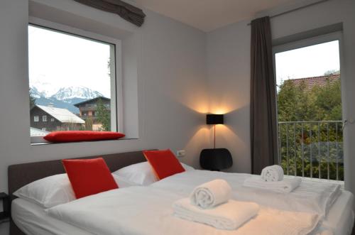 滨湖采尔泽尔时见五季公寓的一间卧室配有白色的床、红色椅子和窗户