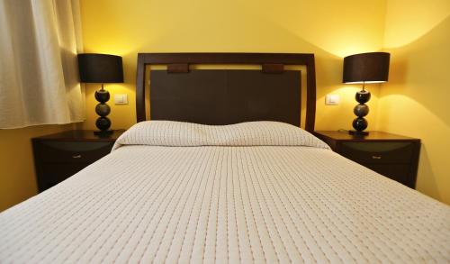 特尔德瓦斯科达伽马公寓的卧室配有一张白色床、两个床头柜和两盏灯。