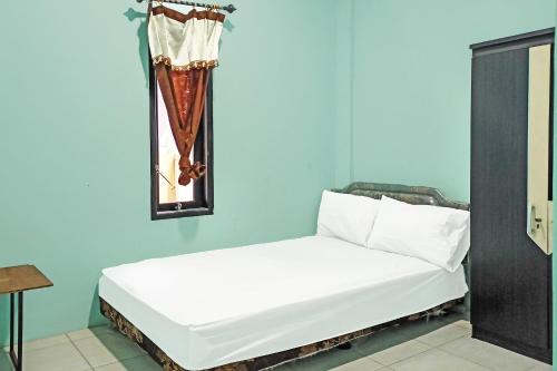 打拉根SPOT ON 91791 Homestay Surya Syariah的蓝色客房内的一张白色床,配有镜子