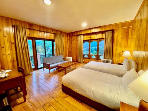 帕罗Taktsang Village Resort的一间卧室配有两张床、一张沙发和一张桌子