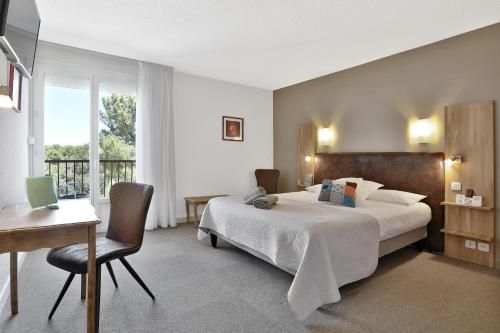 多维勒Hotel Restaurant Logis Le Tropicana的配有一张床、一张书桌和一扇窗户的酒店客房