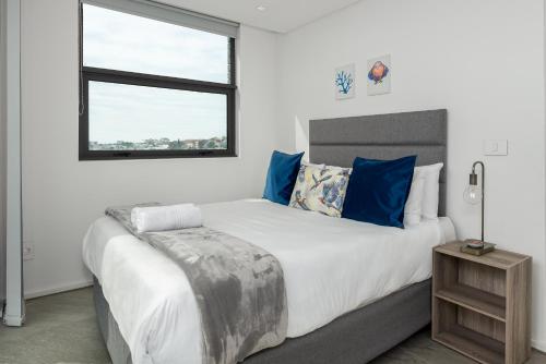 开普敦The Iron Works Apartments的一间卧室配有一张带蓝色枕头的大床和窗户。