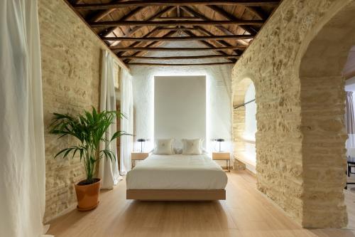 科尔多瓦La Posada De Sojo的卧室配有石墙内的白色床