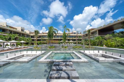 图卢姆MISTIQ Tulum Luxury Apartments的一座度假村游泳池,其背景是度假村
