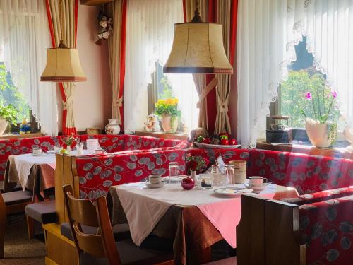 CainesTannerhof Bed & Breakfast的一间设有两张桌子和红色隔间的餐厅