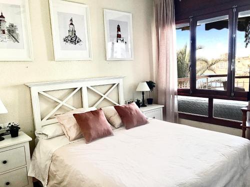 阿桂拉斯Primera Linea de Playa con vistas al Mar的卧室配有带枕头的白色床和窗户。