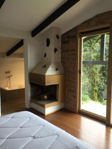 奥塔瓦洛Neblina Bird的卧室设有砖砌壁炉,毗邻窗户