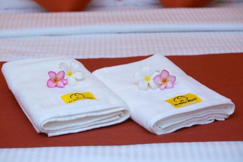 达瓦拉维Ali Weta Safari Resort的两条毛巾,上面有鲜花,坐在桌子上