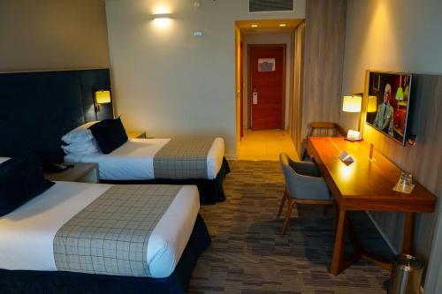 利纳雷斯Hotel Parada Linares的酒店客房配有两张床和一张书桌