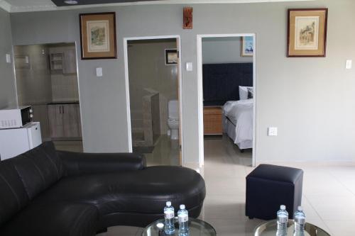 开普敦MO MAJOR的客厅配有黑色真皮沙发和床。