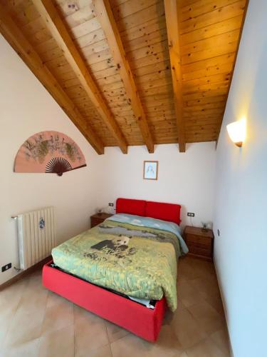 Ceppo MorelliAttico sul Rosa的一间带红色床的卧室,位于带木制天花板的房间内