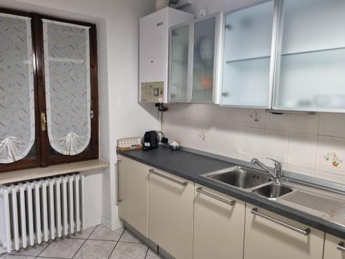 阿佐诺圣保罗SWEET HOME的厨房配有白色橱柜、水槽和窗户。