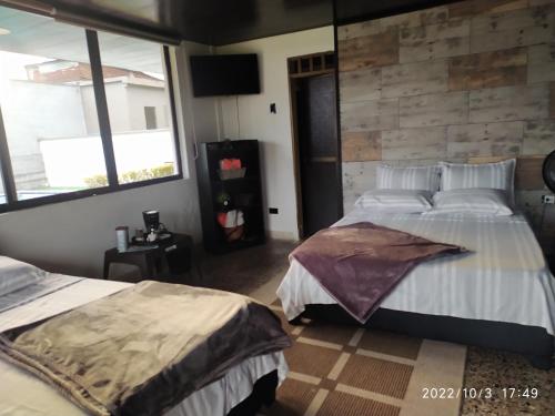布埃纳文图拉Villa Juliana的一间卧室设有两张床和砖墙