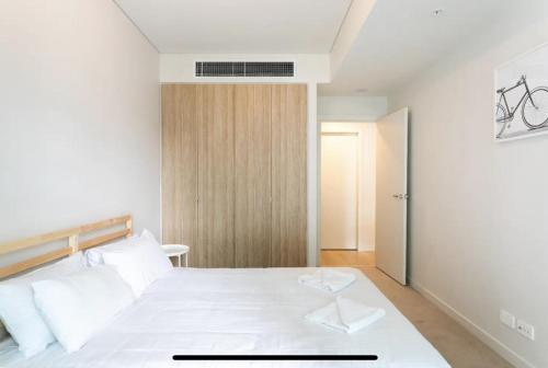 悉尼Lovely One Bedroom + Study with Infinity Pool的卧室配有白色的床和木门