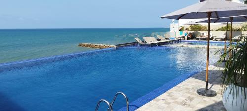 曼塔Departamento Suite frente al mar Poseidon Manta的一个带遮阳伞的游泳池以及大海
