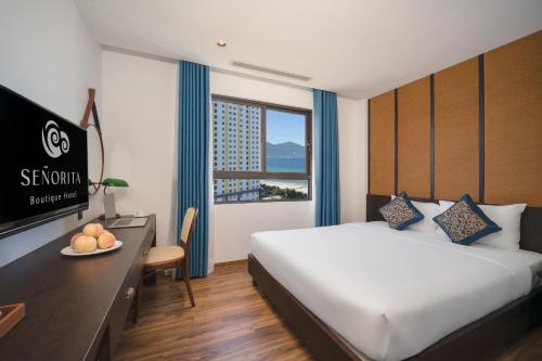 岘港Señorita Boutique Hotel的酒店客房配有一张床、一张书桌和一台电视。