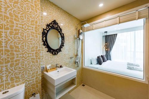芭东海滩LullaBella Hotel的一间带水槽和镜子的浴室以及一张床