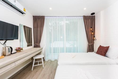 芭东海滩LullaBella Hotel的酒店客房设有两张床和窗户。