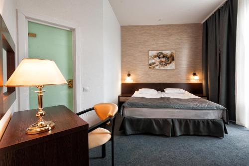 卡拉甘达Chaika Gostinichny Kompleks的酒店客房配有一张床和一张带台灯的书桌
