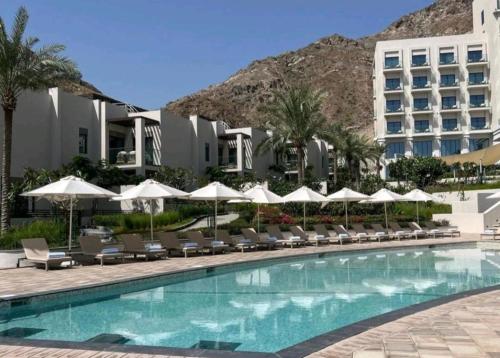 富查伊拉Luxury sea view Apartment In Address Hotel Fujairah的游泳池,带椅子和遮阳伞