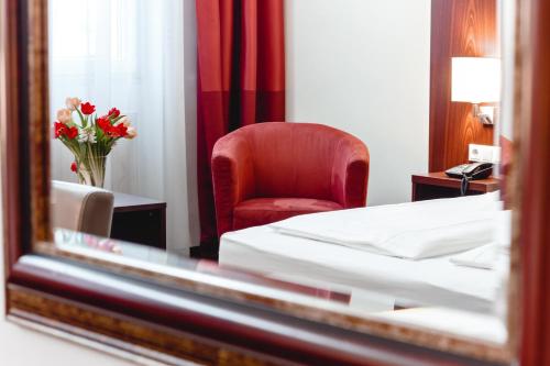 维也纳维也纳俄兰格娆酒店的一间卧室配有一张床、一张红色椅子和一面镜子