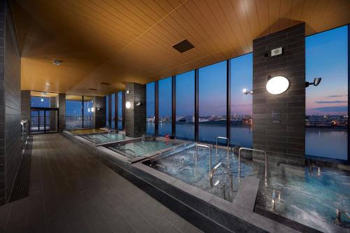 东京Villa Fontaine Grand Haneda Airport的大楼内带两个热水浴缸的大浴室