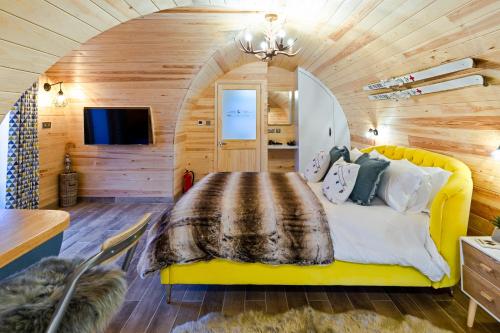 赫尔姆斯利Cliff Stud Retreat - Luxury lodges and cosy cottages的一间设有黄色床的卧室,位于一个木墙的房间