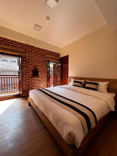 帕坦KGH Patan的一间卧室设有一张大床和砖墙