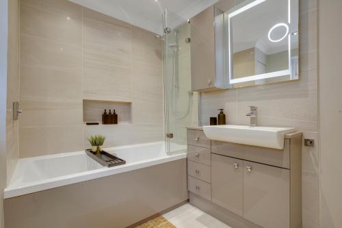 斯坦维尔Ashford, Legoland, Windsor, Heathrow Serviced House的带浴缸、水槽和淋浴的浴室