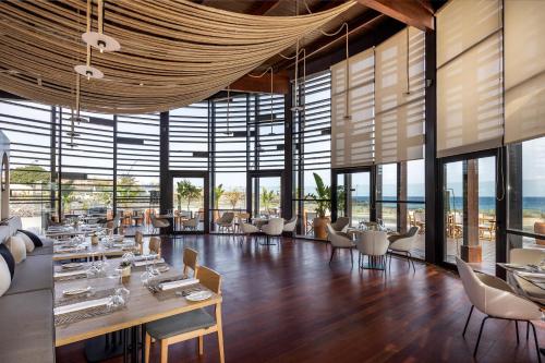 圣米格尔德阿沃纳Barceló Tenerife Royal Level的餐厅设有桌椅和大窗户。